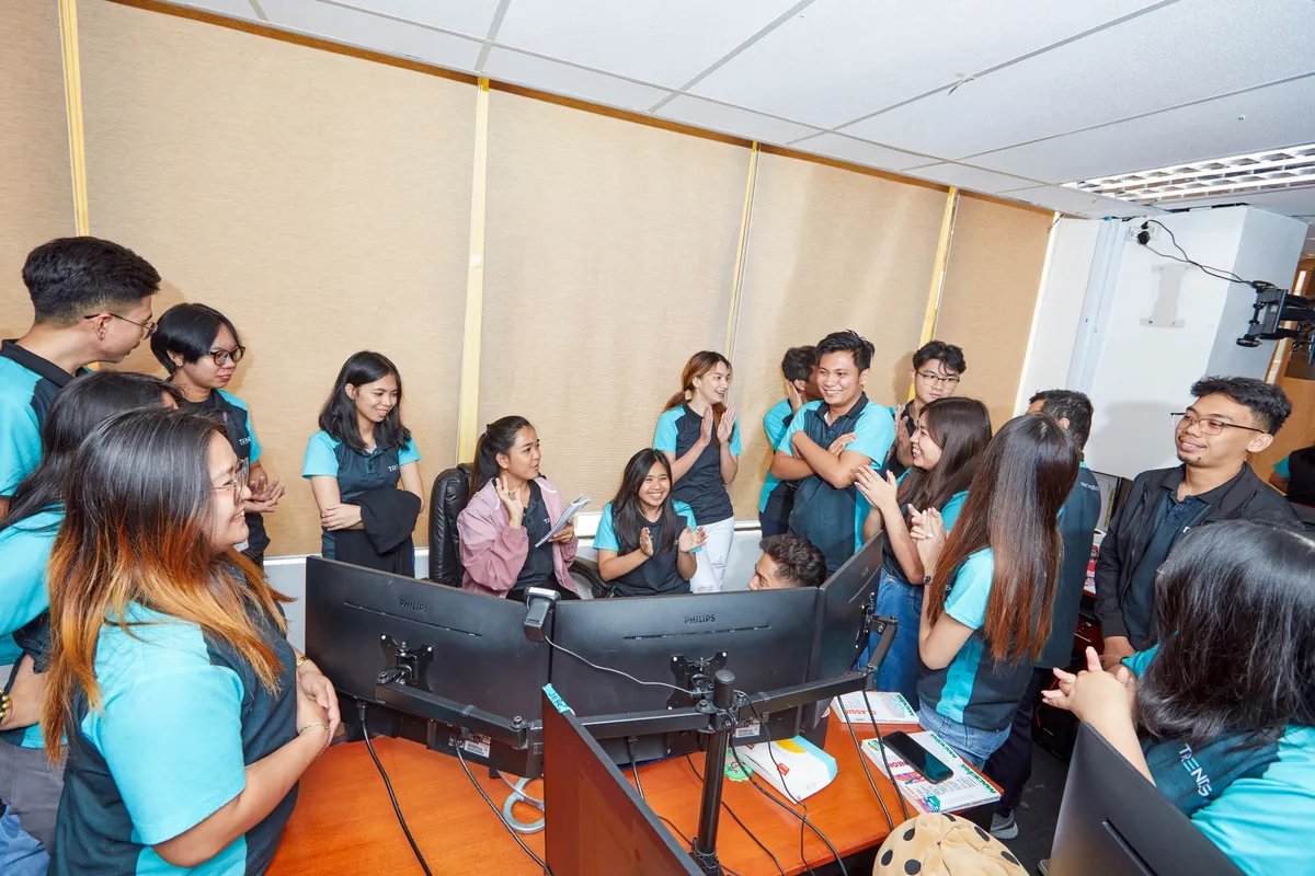 Colleagues gathered around computer workstations in our Philippines office